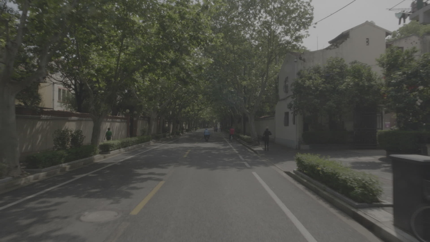 tour by residential district in Shanghai with green trees tunnel, people walking, bicycles, bike path, traditional architecture facades
