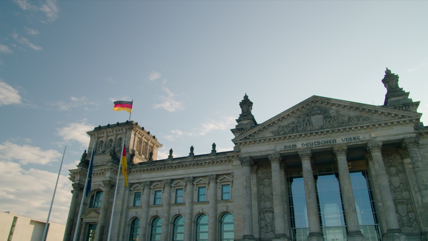 Panoramic View of Bundestag - German federal parliament in Berlin. Earlier Reichstag as Main Architecture and EU Politics Landmark with Waving Flags. 4K Wide Panning establishing shot