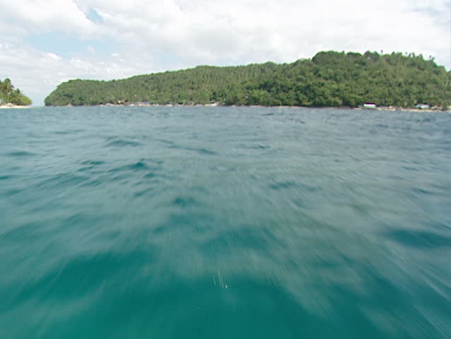 A shot moving over the pacific ocean close to the water with an island in the background in Manila, Philippines