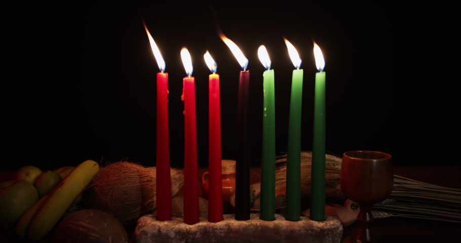 Kwanzaa table with a Kinara lit with Red green and black candles zoom out slow motion Royalty-Free Stock Footage #1080765044