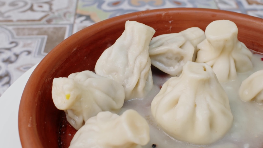 Georgian meal khinkali in clay bowl spinning round on table