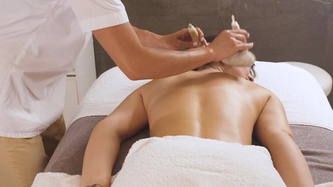 woman gets a massage with herbal bags