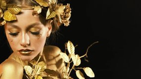 portrait of woman, golden skin. Girl in wreath, gold roses flowers. Beautiful face steel glitter art makeup eyes look at camera. black studio background. fashion model posing, yellow shadows sparkles