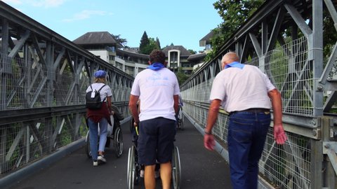 Lourdes, France - August 28, 2021: Pilgrims, accompanying patient staff and invalid people on wheelchairs are returning from the Lourdes cave after the prayer