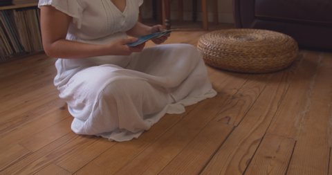 woman in white clothes playing with astral cards while sitting on wooden floor, static view