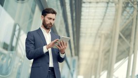 stylish bearded businessman in formal business suit standing working with tablet in hands on background modern office building outside. Man using smartphone or uses mobile phone outdoors city street - Powered by Shutterstock - Get 15% off with code: PIKWIZARD15