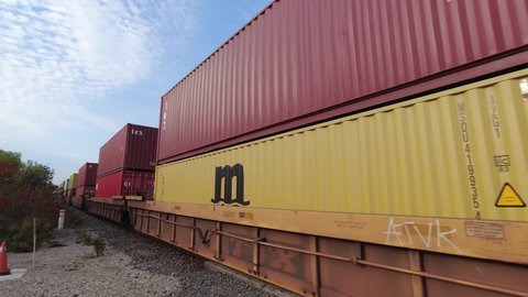 Toronto, Ontario, Canada - October 11, 2021: Freight train. Cargo train passing through railroad in rural area. Canadian railway and moving long train containers. American locomotive transportation.