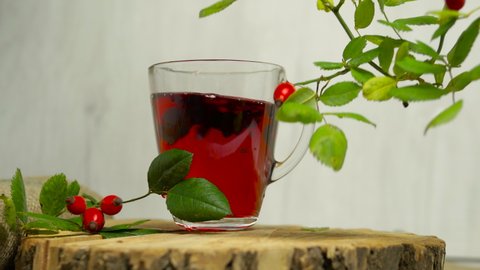 Tincture of herbs and red berries, tea from medicinal rose hips on a wooden background, homeopathy