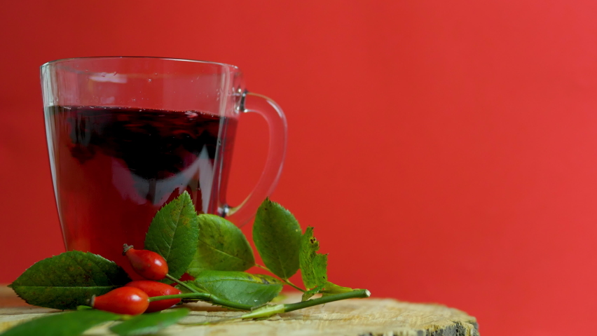 Healing red tea from wild rose berries on a red background on a wooden, homeopathic herbal infusion. Red rosehip drink Royalty-Free Stock Footage #1080807296