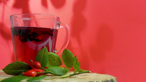 Healing red tea from wild rose berries on a red background on a wooden, homeopathic herbal infusion. Red rosehip drink