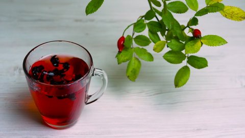 Healing red tea from rose hips on a wooden background, homeopathic herbal infusion. Red rosehip drink