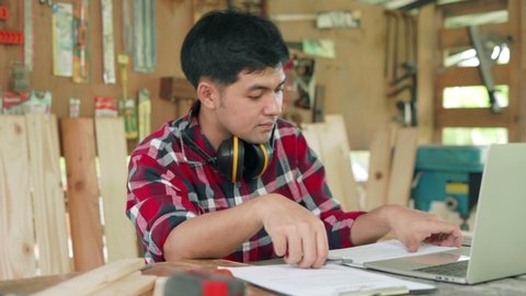 Small business owner carpentry concept. Asian man owns recheck wood furniture. carpenter is Recheck straight of wood before manufacturing. Comparison of material with designs.