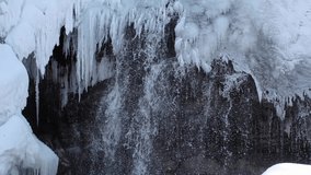 Video of frozen waterfall on river Pescherka in winter season.  Jets of water flow from under the long icicles. Siberia, Russia