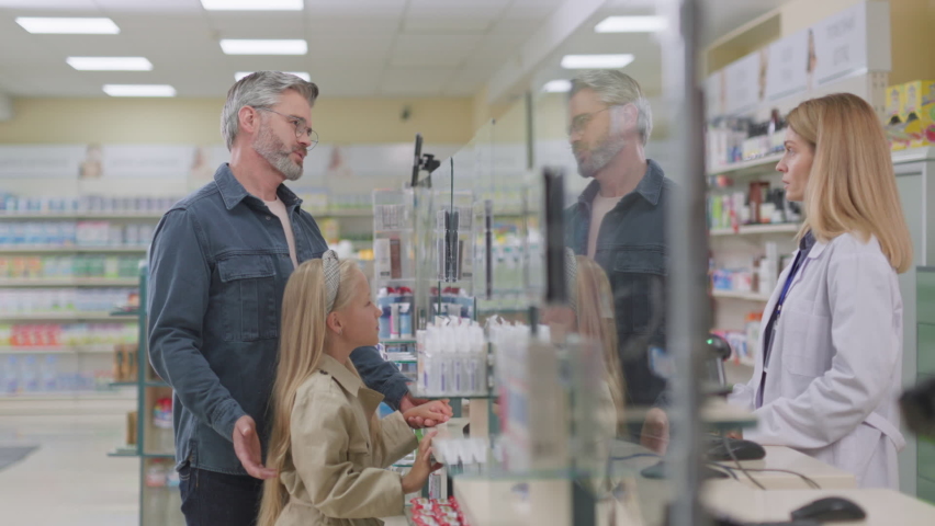 Mature caucasian father with young cute daughter visiting drugstore. Pharmacy polite female worker advising modern medicine product at apothecary. Royalty-Free Stock Footage #1080814232