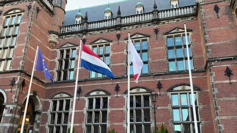GRONINGEN, NETHERLANDS - 15. OCTOBER 2021: European, Dutch and RUG Flag slowly waving in the Wind, in Front of the University of Groningen.