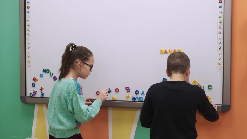 Two children compete to form words on a magnetic board during a lesson in class.School for Children, Teaching Adolescents, Gain Knowledge, Learn the Language.