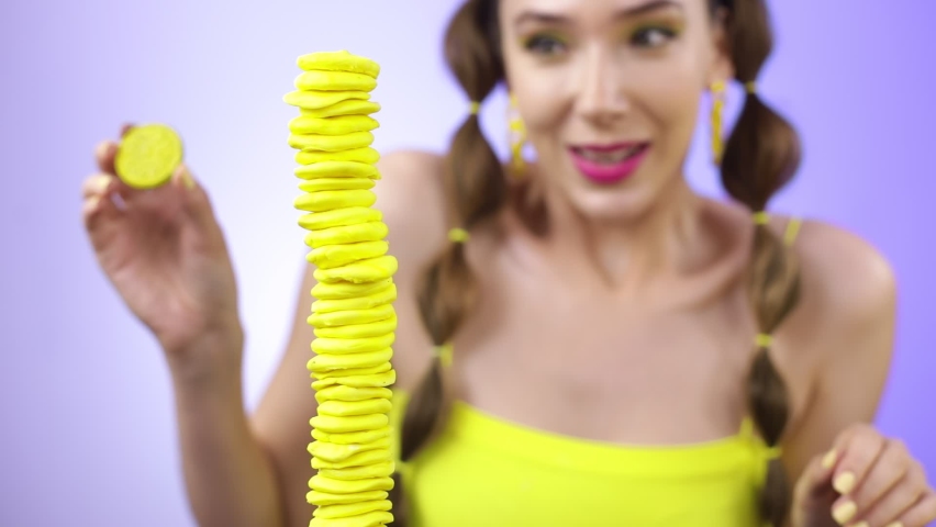 A cheerful girl makes a tower of yellow sweets.