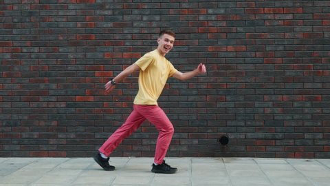 Playful crazy man dance emotions. Dancing man funny break dance, happy rhythmically waving his arms on textured street wall. Breakdancing, street dancing, hiphop, freestyle dance. Lifestyle 