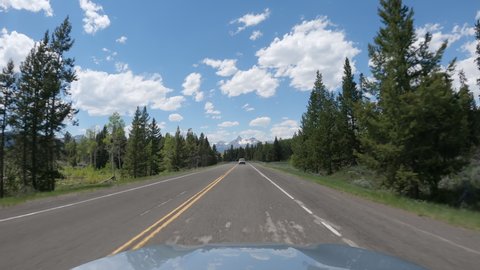 POV Driving a car on asphalt road in Montana mountains leading to Yellowstone National Park