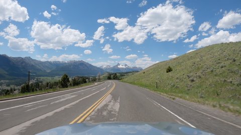 Driving a car on asphalt road in Montana mountains leading to Yellowstone National Park