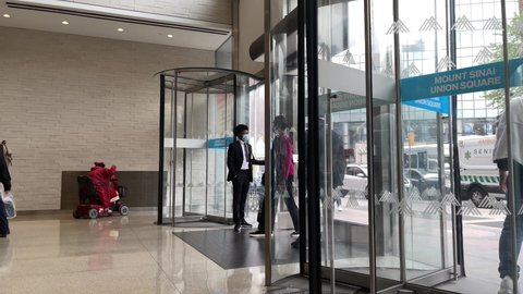 NYC, USA - OCT 13, 2021: people entering and exiting Mount Sinai Union Square medical center hospital revolving door entrance Manhattan New York City.