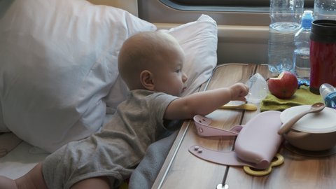 Family with little child traveling by train, cute 6 months old baby boy lying on seat by window in a compartment train. High quality 4k footage