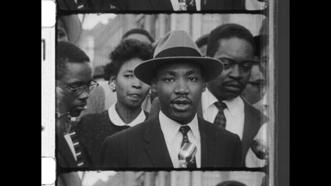 1955 Montgomery, AL. Dr Martin Luther King Jr speaks to reporters about the importance of nonviolent "attitude of love," after the The Montgomery Bus Boycott. 4K Overscan of Vintage Archival 16mm Film