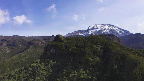 4K Drone footage camera rising above forest-covered valley near Mt Kilimanjaro. Environment, mountains, nature concept.