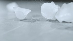 SLOW MOTION, MACRO, DOF: Odd shaped ice cubes fall and bounce around the marble countertop. Melting pieces of ice get scattered across the empty dining table. Ice cubes bouncing around the counter. - Powered by Shutterstock - Get 15% off with code: PIKWIZARD15
