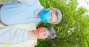 Authentic shot of asian elderly couple wearing face mask have video chat by mobile phone happily outdoor in vertical position