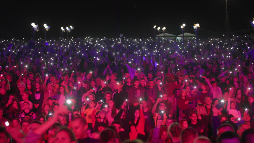 KHERSON, UKRAINE-SEPTEMBER 7, 2021: Festival Melpomene of Tavria, entertainment, crowd of people waving hands with mobile phone lights during live music concert at night