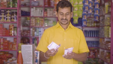Happy smiling Groceries or Kirana Merchant small business owner Counting money - concept of Successful business, profit making, banking and finance.