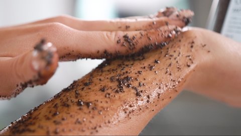 close-up female smears her body with a coffee scrub, runs over hand, massages skin, makes cleansing, peeling, skin care, procedure makes smooth movements, removes dead cells, salon, cleansing care 