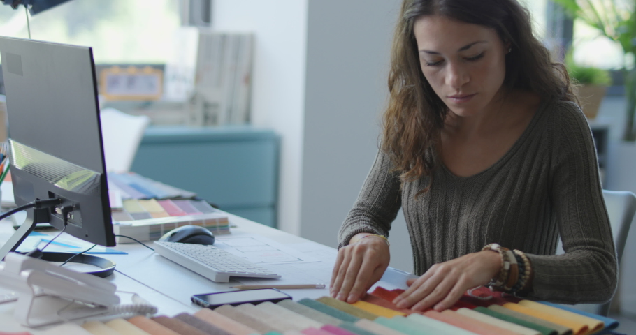 Young interior designer working in her studio, she is choosing fabric swatches and using her computer Royalty-Free Stock Footage #1080861167