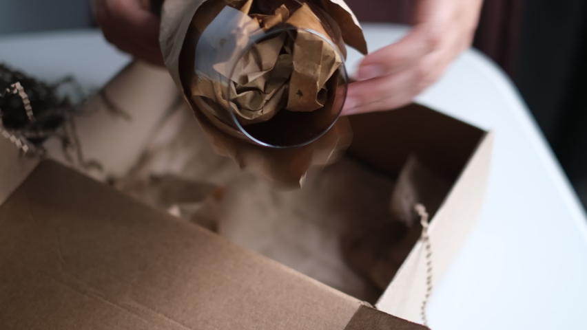 woman at home opening carton box, just delivered parcel on address. Mail delivery to house. fragile glass, delicate delivery of fragile items