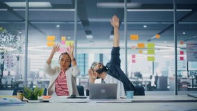 Two Happy Young Professionals in Office: Black Businesswoman and Hispanic Businessman Dance Together, Smile Looking at Camera, Sitting at Desk. Specialists Work in Creative Office, Celebrate Success - Powered by Shutterstock - Get 15% off with code: PIKWIZARD15