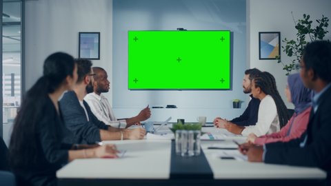 Multi-Ethnic Office Conference Room Meeting: Diverse Team of Successful Managers, Executives Talk, Use Green Screen Chroma Key TV. Businesspeople Investing in eCommerce Startup. Wide Static Shot