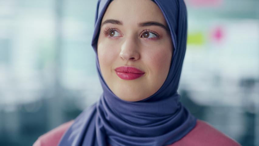Portrait of Muslim Businesswoman Wearing Hijab Looks at Camera and Smiles. Beautiful Woman Wearing Traditional Headscarf. Successful Empowered Arab Woman. Bokeh Out of Focus Background Royalty-Free Stock Footage #1080878474