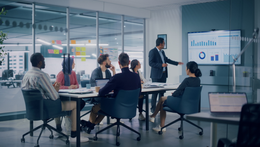 Multi-Ethnic Office Conference Room. Indian CEO does Presentation for Diverse Young Specialist, Talking, Using TV with Infographics, Statistics, Graphs. Businesspeople Develop e-Commerce Startup Royalty-Free Stock Footage #1080878552