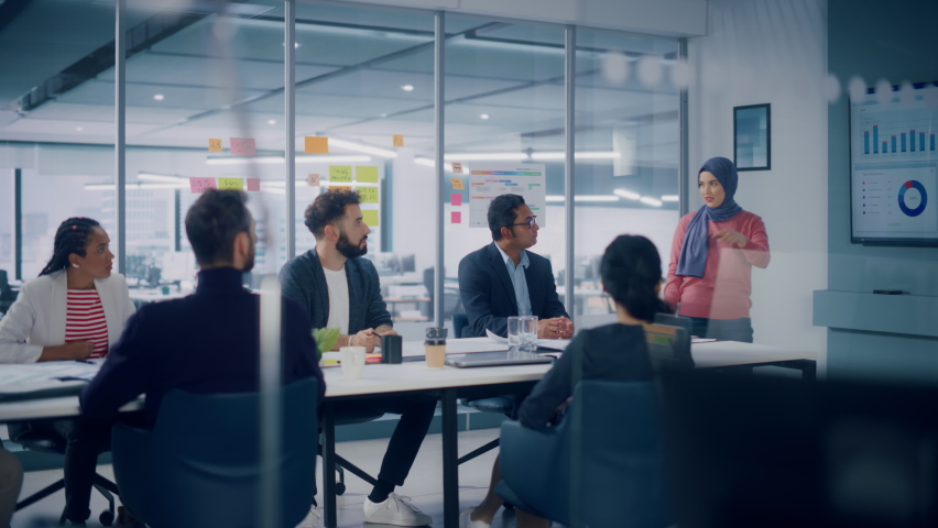 Multi-Ethnic Office Conference Room. Muslim Female CEO Wearing Hijab does Presentation for Group of Managers Talk, Use TV Infographics, Statistics. Businesspeople Brainstorm eCommerce Growth Strategy | Shutterstock HD Video #1080878555