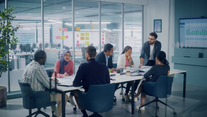 Multi-Ethnic Office Conference Room Meeting: Diverse Team of Creative Entrepreneurs, Specialists Talk, Use TV for infographics. Businesspeople work on Digital e-Commerce Startup. Static Wide Shot