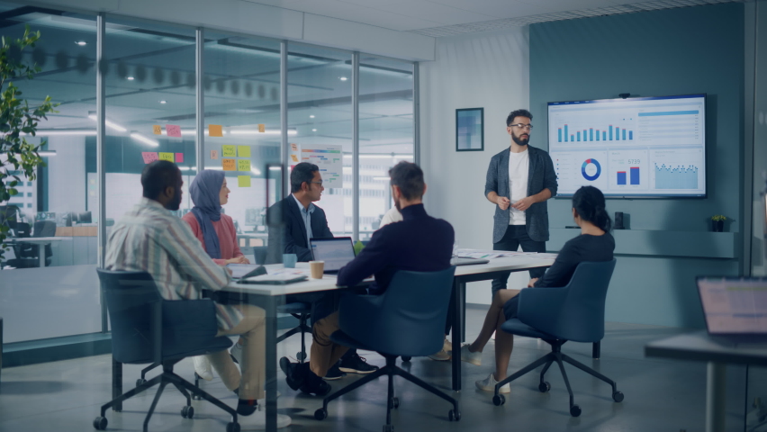 Diverse Modern Office: Motivated Latin Businessman Leads Business Meeting with Managers, Talks about Company Growth, Uses TV for Presentation. Creative Digital Entrepreneurs Work on e-Commerce Project