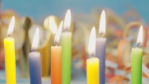 Close up of blow off colorful birthday candels isolated on blue background shot in 4k super slow motion