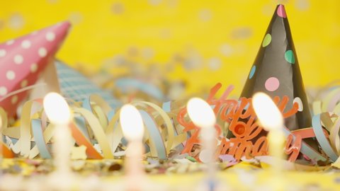 Close up of party decoration burning candels party hats streamers isolated on yellow background shot in 4k super slow motion