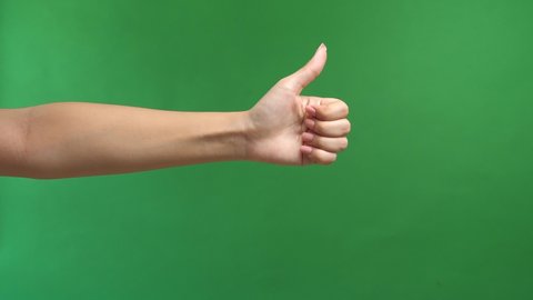 Closeup Of Female Hand Showing Thumbs Up Sign Against Green Screen Background
