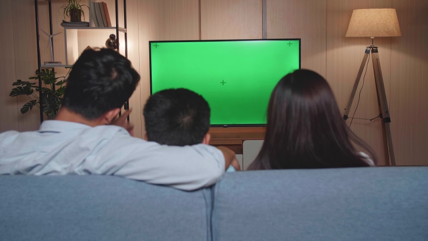 Back View Of Asian Family, Leisure And People Concept, Father, Mother And Little Son Watching Tv With Mock Up Green Screen At Home
