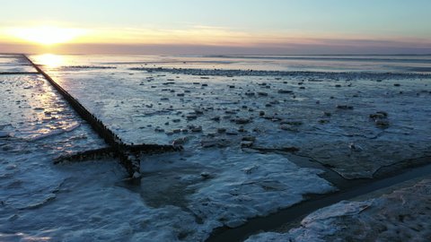 Aerial from a frozen Wadden Sea in winter in Friesland the Netherlands at sunset