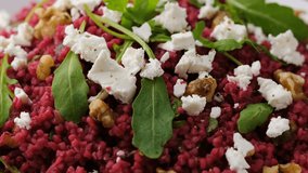 Bulgur salad with beetroot, nuts, arugula and feta cheese. Healthy diet food. Rotating video