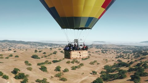 Dutch city Solvang in California, 4K USA, June 2019. Happy excited tourists waving hands while flying in Hot air balloon basket. Aerial circling shot around hot air balloon with basket with tourists