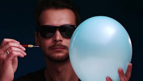 European man in sunglasses bursts a blue balloon with a dart - Powered by Shutterstock - Get 15% off with code: PIKWIZARD15